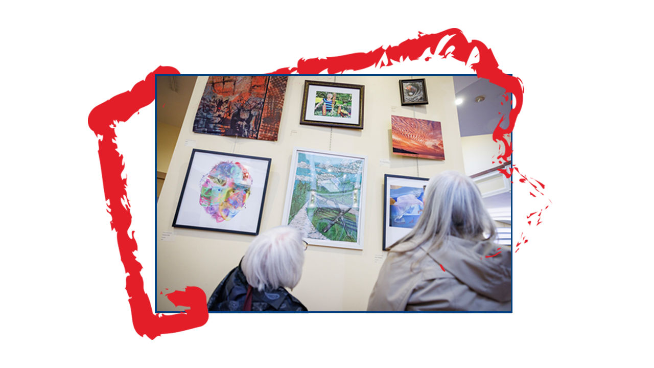 People looking at wall of artwork