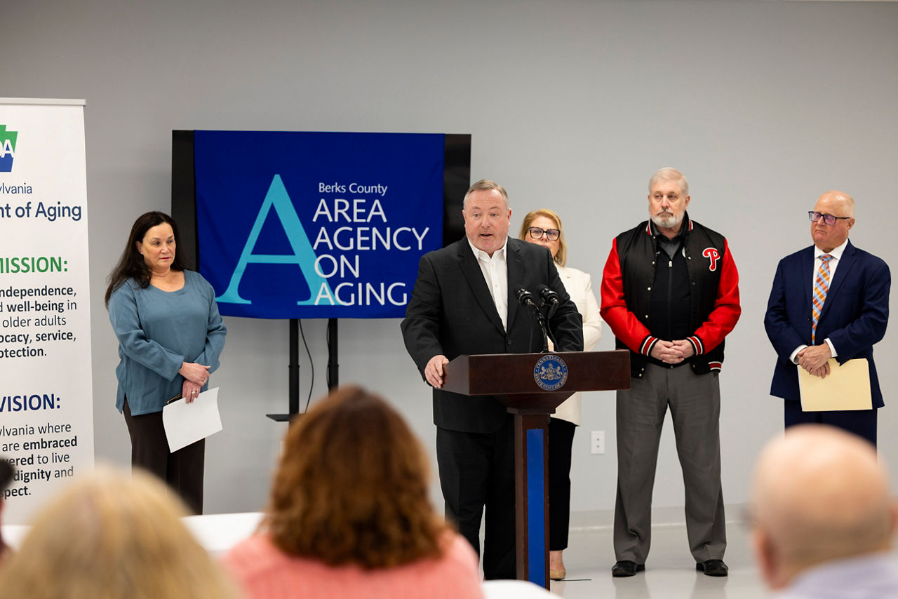 Secretary Kavulich and people stand in front of audience