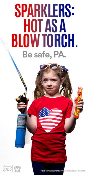 A young girl in patriotic attire holdsl up a box of sparklers in one hand and a blowtorch in another. Text reads: "Sparklers: Hot as a blow torch. Be safe, PA"