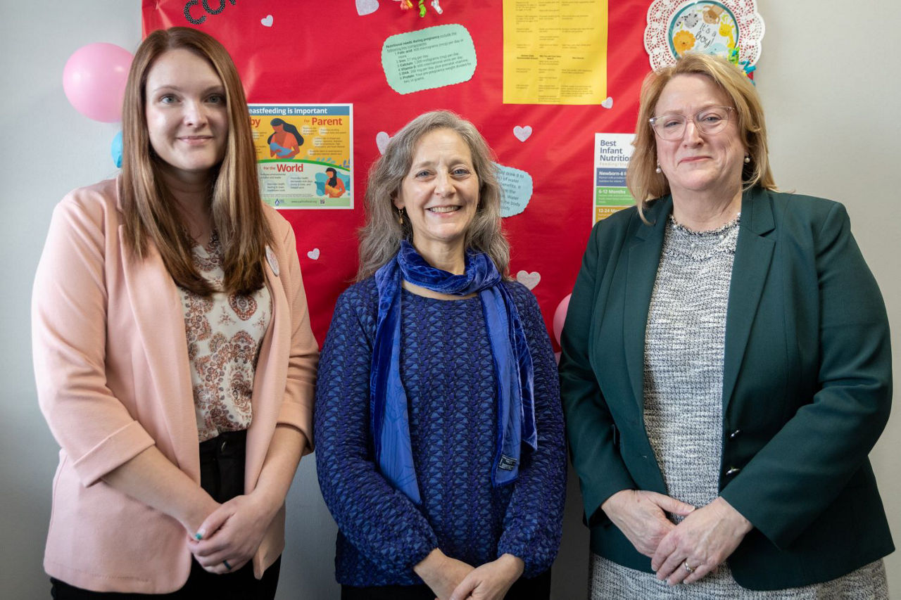 Three women stand smiling