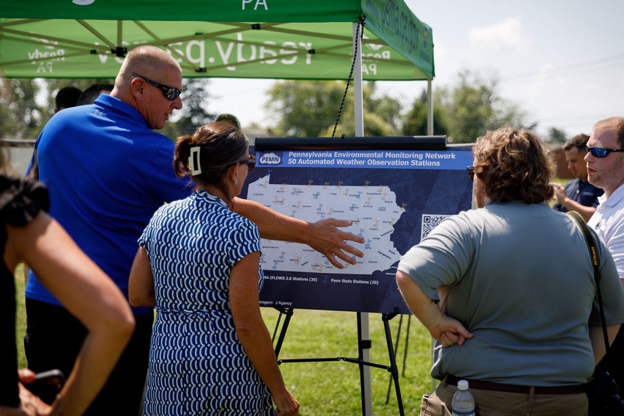 A group of people observe a large map of where new monitoring stations will be set up across Pennsylvania.