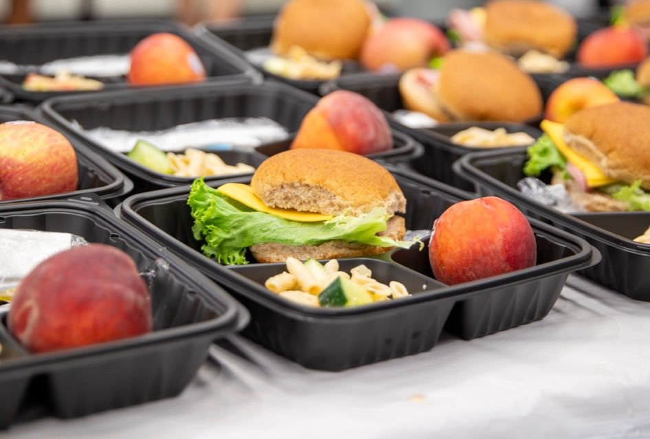Lunch trays with apple, sandwich, and pasta salad