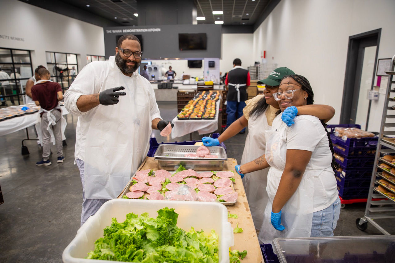 3 workers are shown standing in a kitchen, meal prepping 