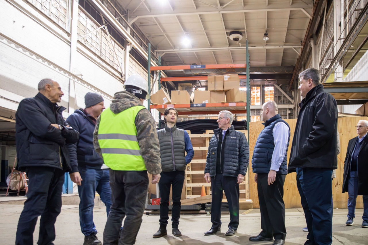 A group of businesspeople tour a packaging facility filled with boxes.