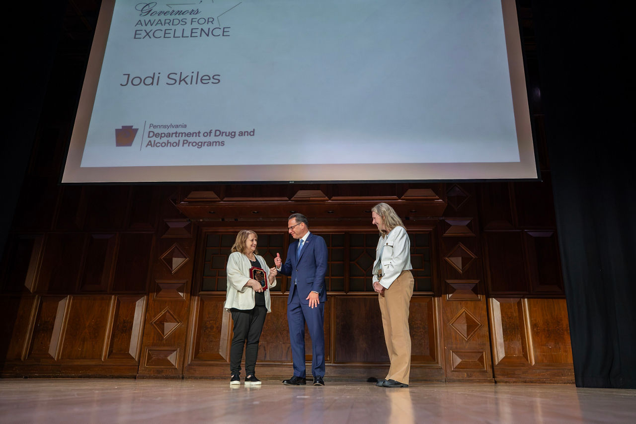 Governor Josh Shapiro stands on stage with Bureau of Program Licensure Director Jodi Skiles and Deputy Secretary Sarah Boateng as Jodi Skiles receives the Governor's Award for Excellence.