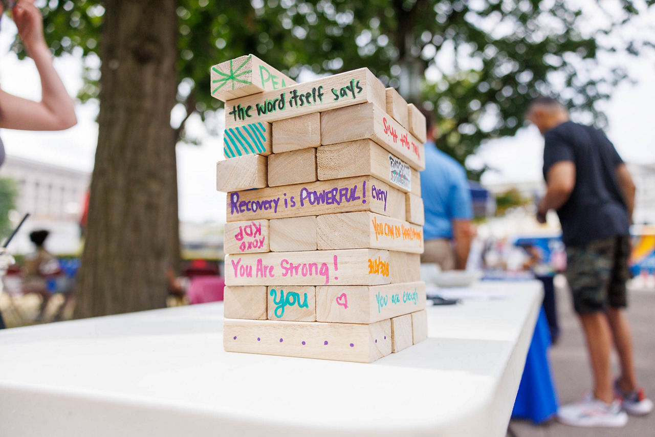 Stack of blocks with recovery inspiration art and words sitting on table at Recovery Month event