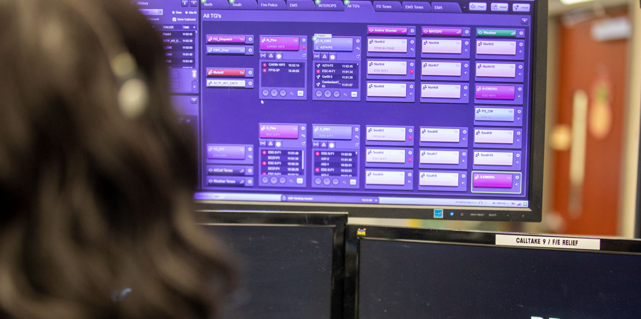 A 911 dispatcher looks at a computer screen.