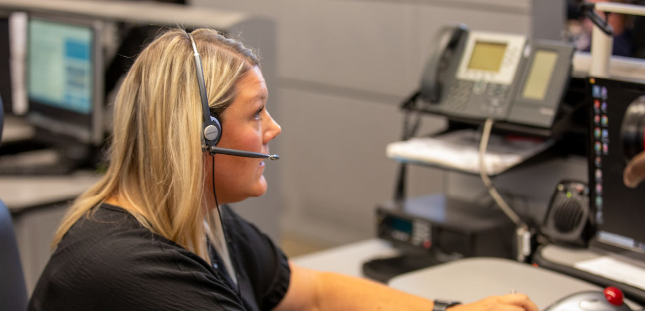 A 911 dispatcher in a headset types while answering a call.