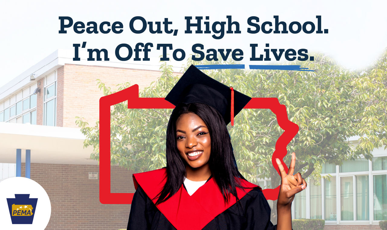 A Black high school graduate with long dark hair holds up a peace sign.
