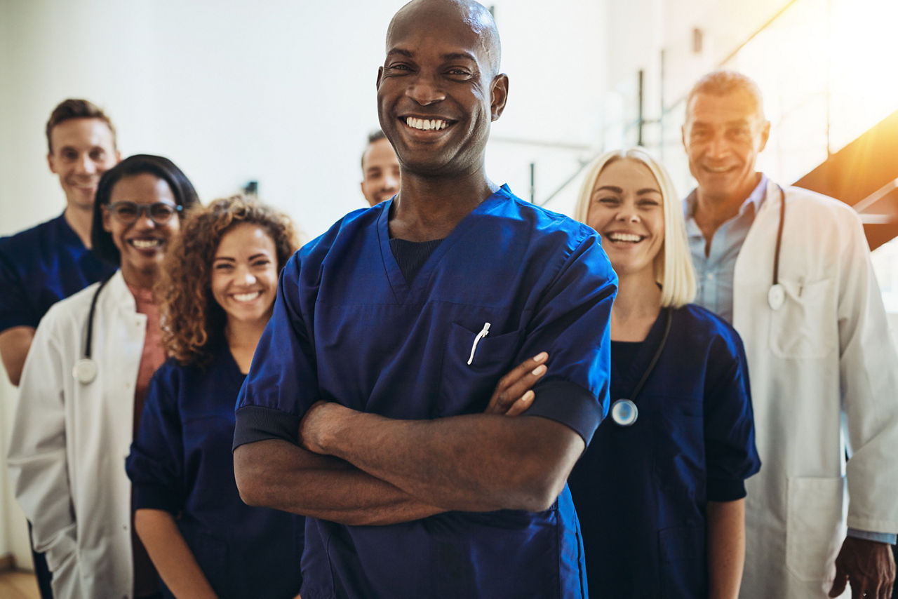 Smiling black doctor standing in a room with other healthcare staff