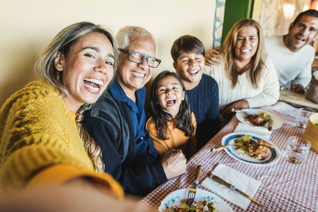Happy latin family doing selfie while eating together at home 