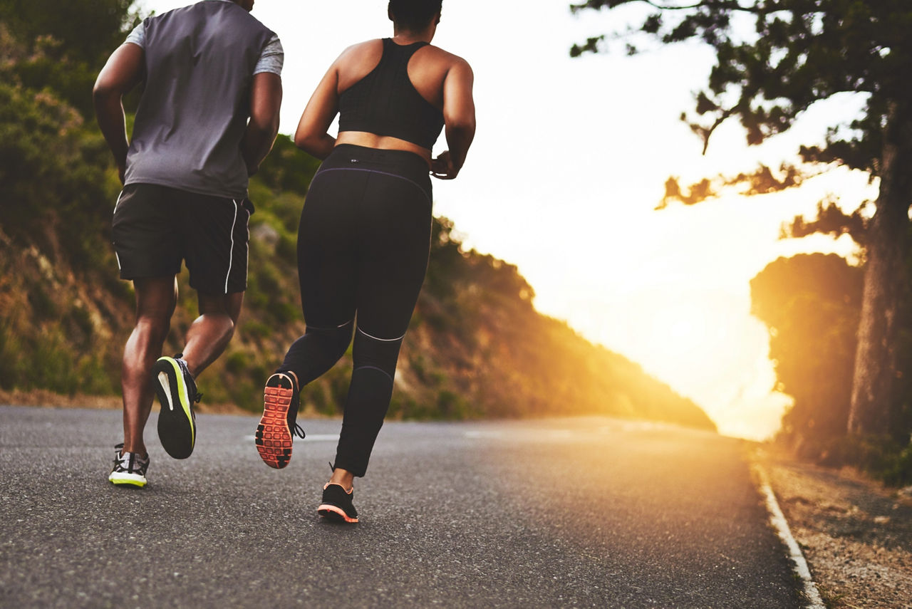 Couple, back and running with sunset on road for workout, training or outdoor exercise together in nature. 