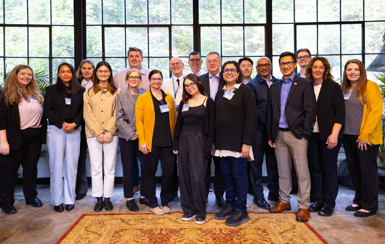 A group of businesspeople pose for a picture in front of a window