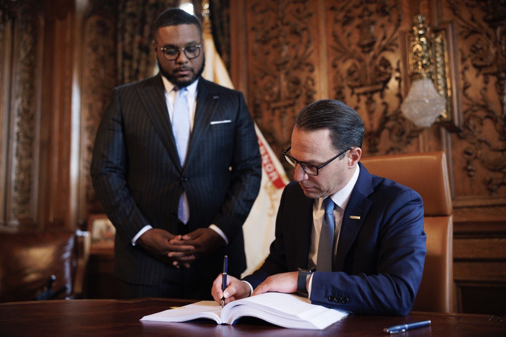 Governor Shapiro signing a budget in his office. 