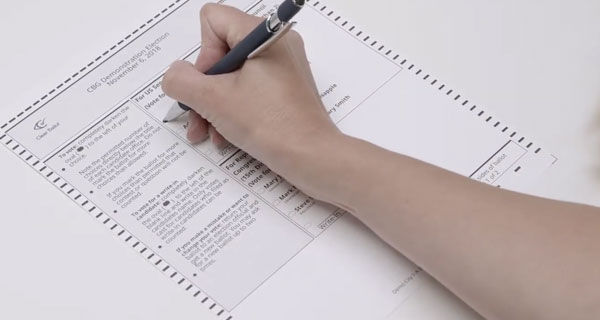 Person filling out a ballot with a pen