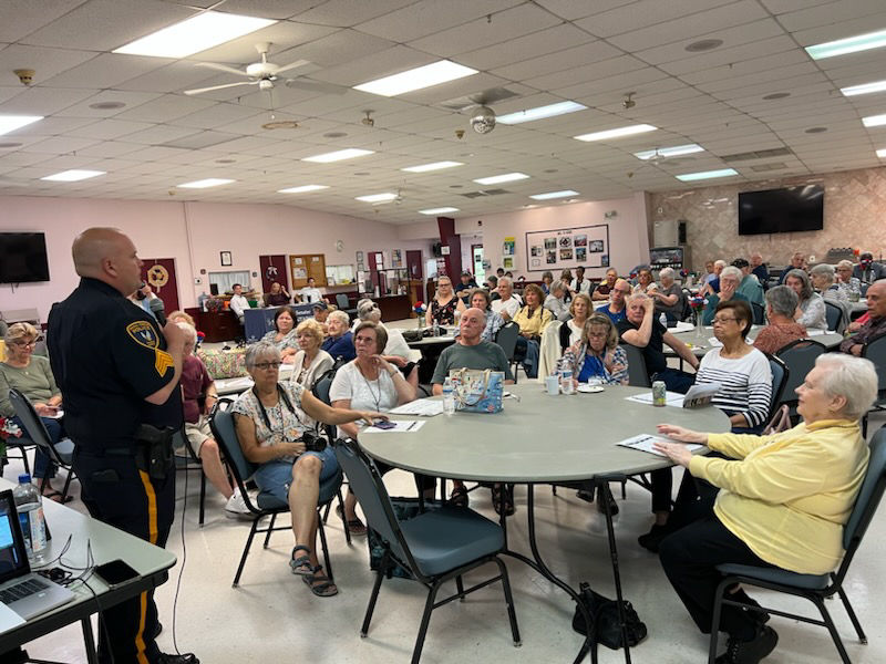 Police officer giving a presentation to a large group of senior citizens as part of our consumer outreach programs.