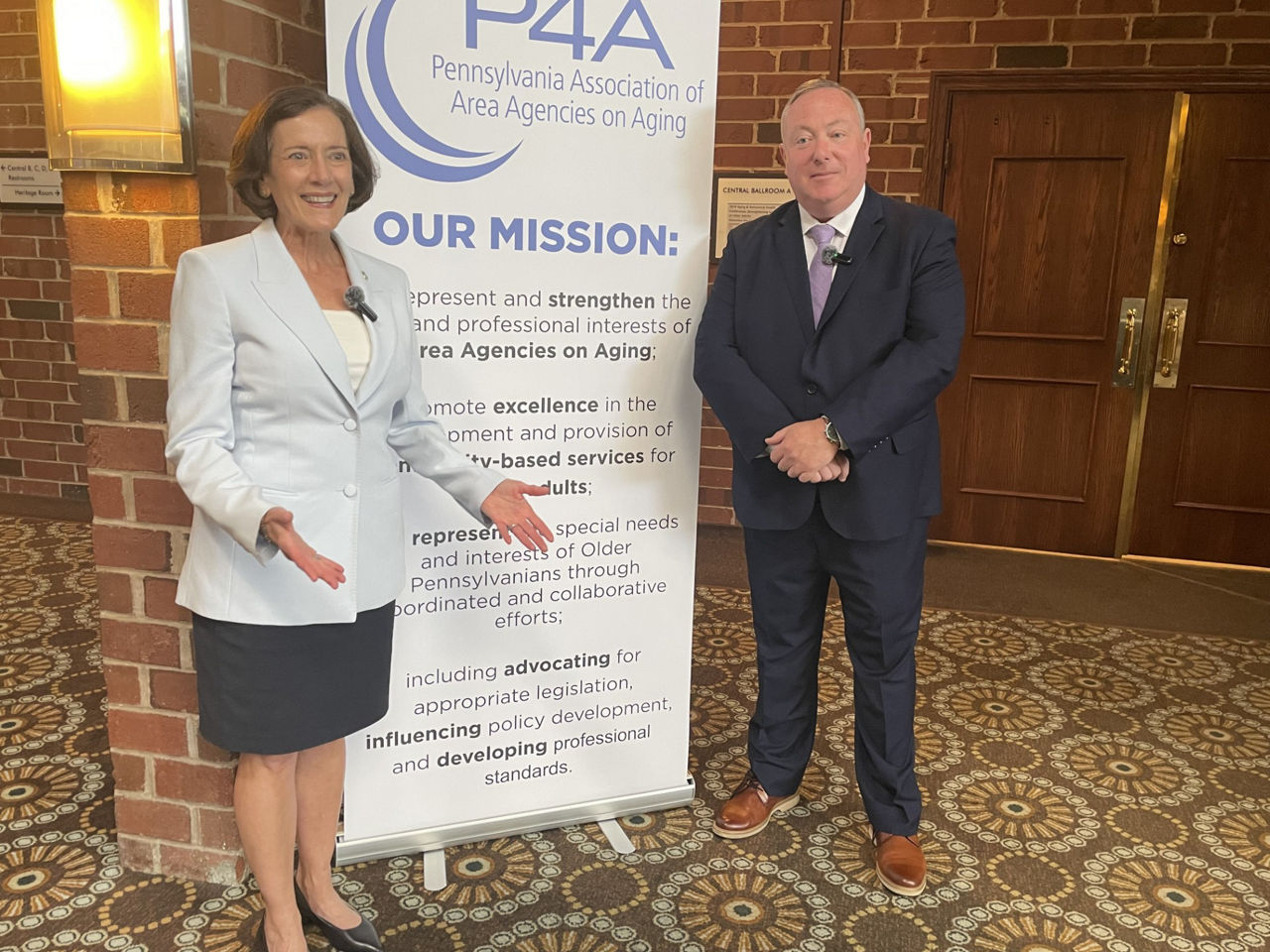 Secretary Dr. Val Arkoosh and Department of Aging (PDA) Secretary Jason Kavulich standing by a P4A banner.