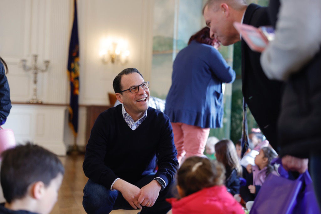 Governor Shapiro crouching on the ground and smiling