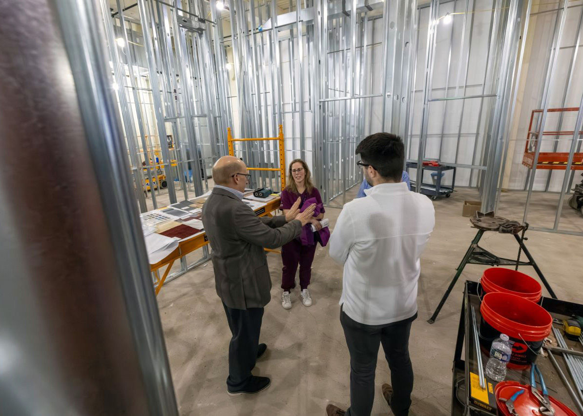 A group of three businesspeople speak to each other in an under-construction laboratory.