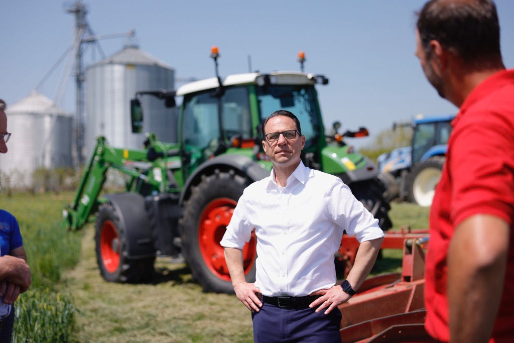 Governor Shapiro talking to someone in front of a tractor
