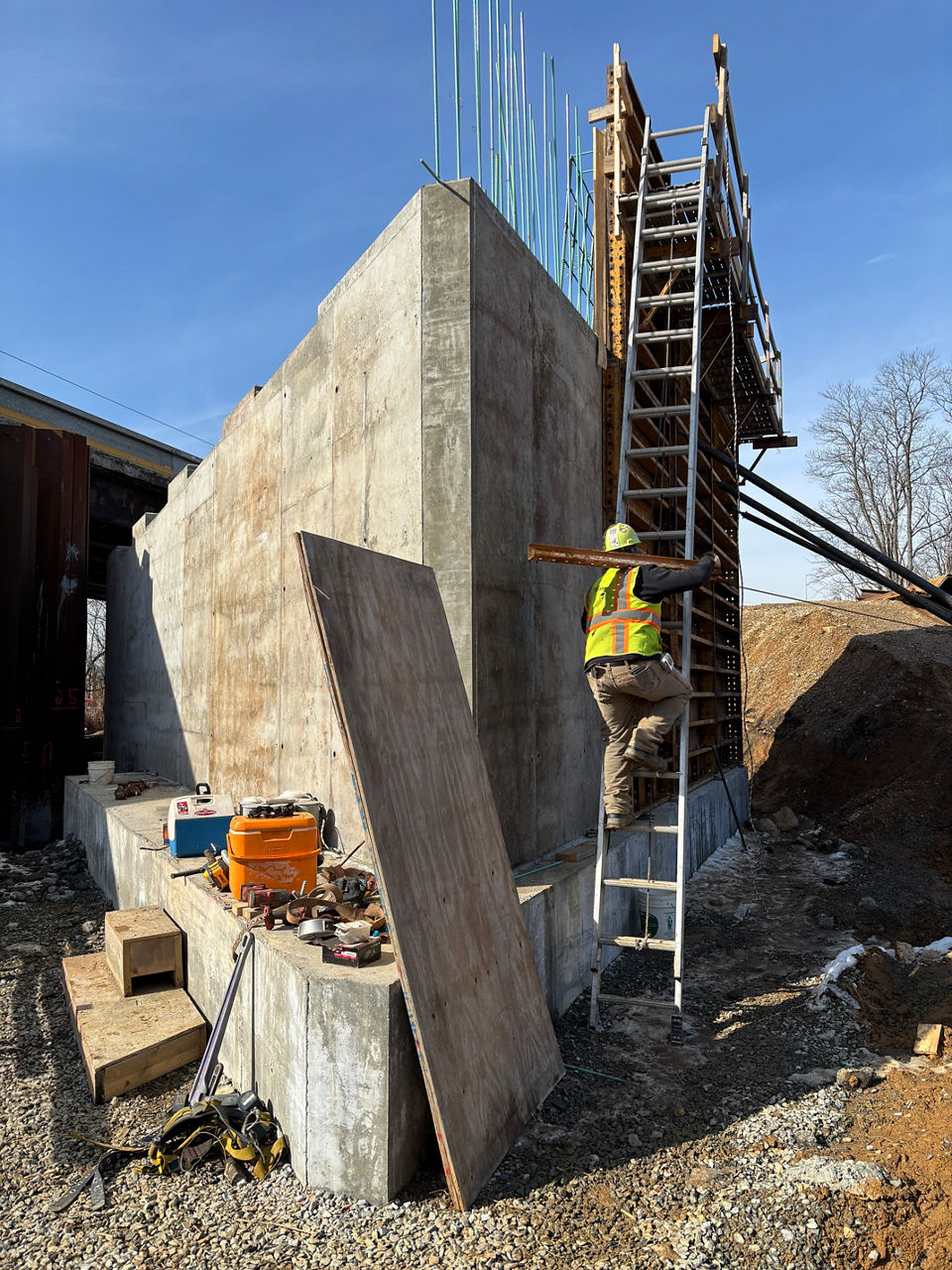 Man climbing ladder to work on new abutment for bridge