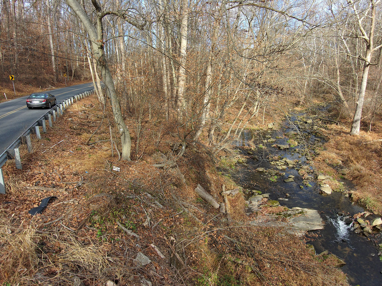 Side view of Bondsville Road retaining wall with car driving along road above the retaining wall. Taken 12-12-25