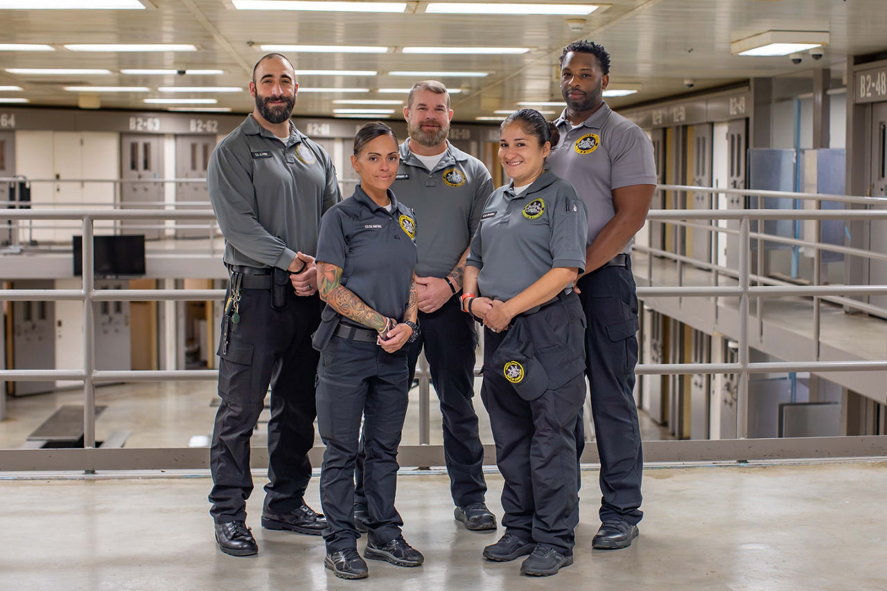 Five corrections officers standing in a housing unit
