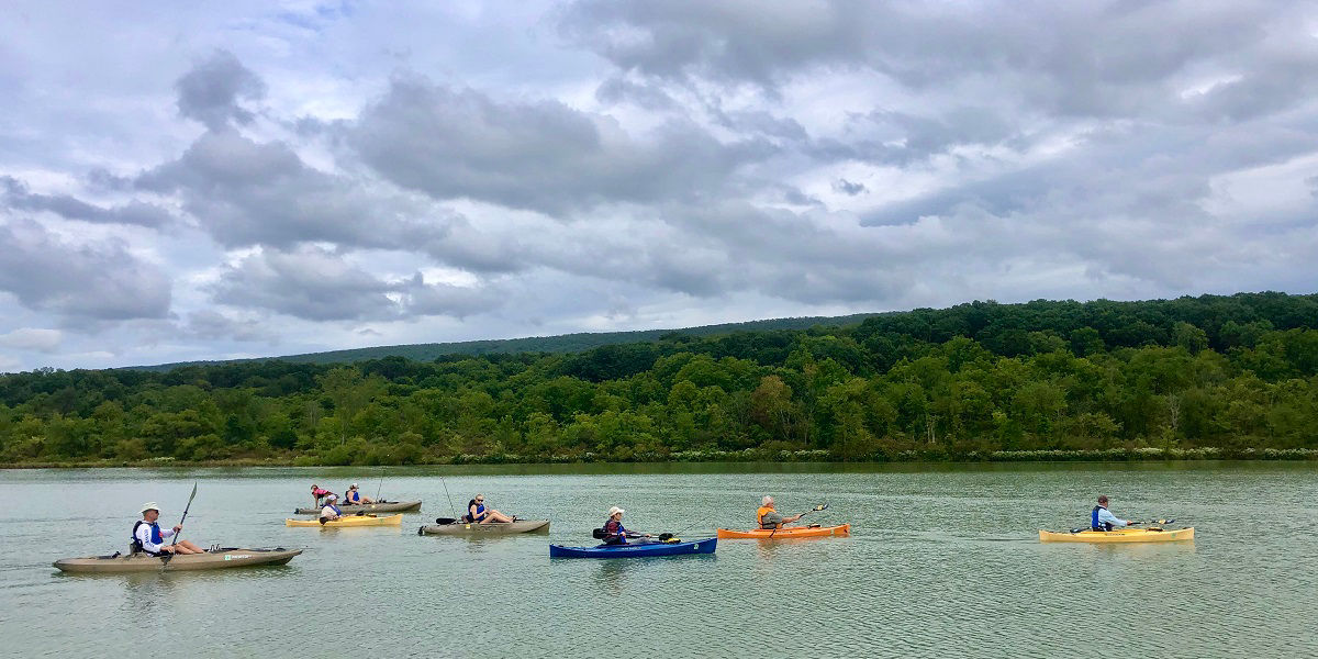 Group of people on lake fishing from kayaks 