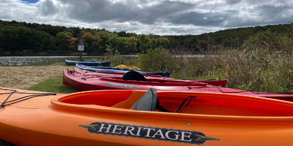 Kayaks sitting on the bank of a lake 