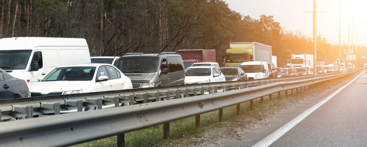 Highway interstate road with car traffic jam and tree forest on background. Motorway bumber barrier gridlock due country border control point. Vehicle crash accident and queue bottleneck on freeway.