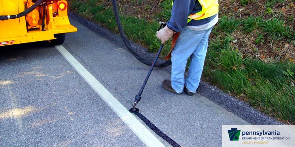 A PennDOT employee conducts seal cracking along the roadway.