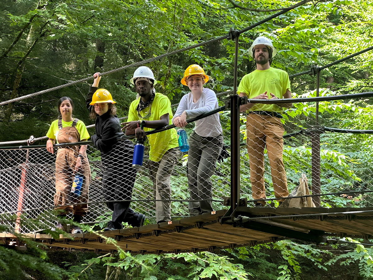 Outdoor Corps ASL Crew Members stand on a rope bridge.