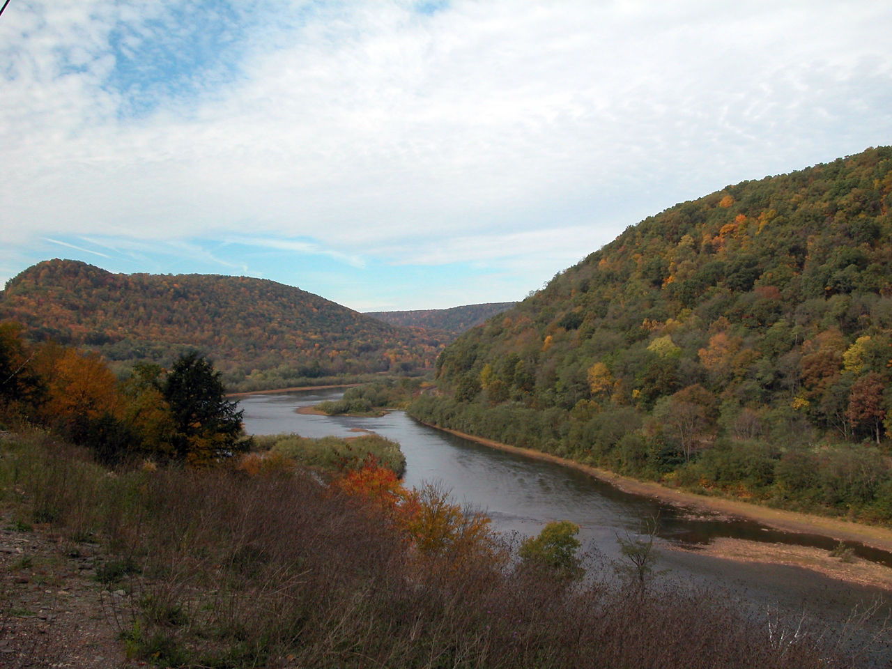 A fall scene of a river flowing through autumn-colored mountains