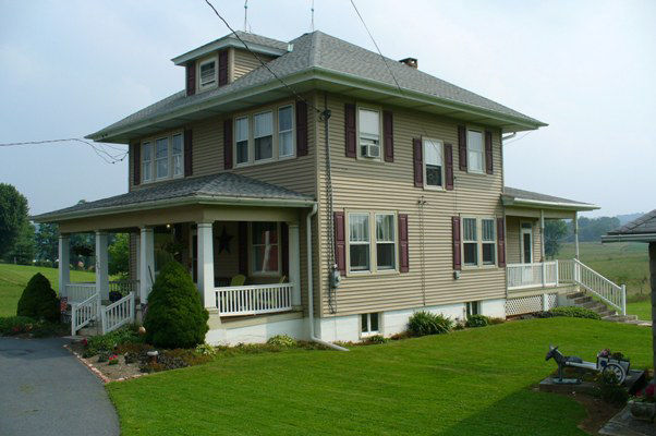 Two-story frame house with front porch and pyramidal roof with dormer.