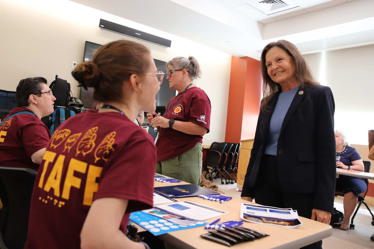 A woman in a maroon staff shirt engages in conversation with Department of Labor and Industry Secretary Nancy A. Walker.
