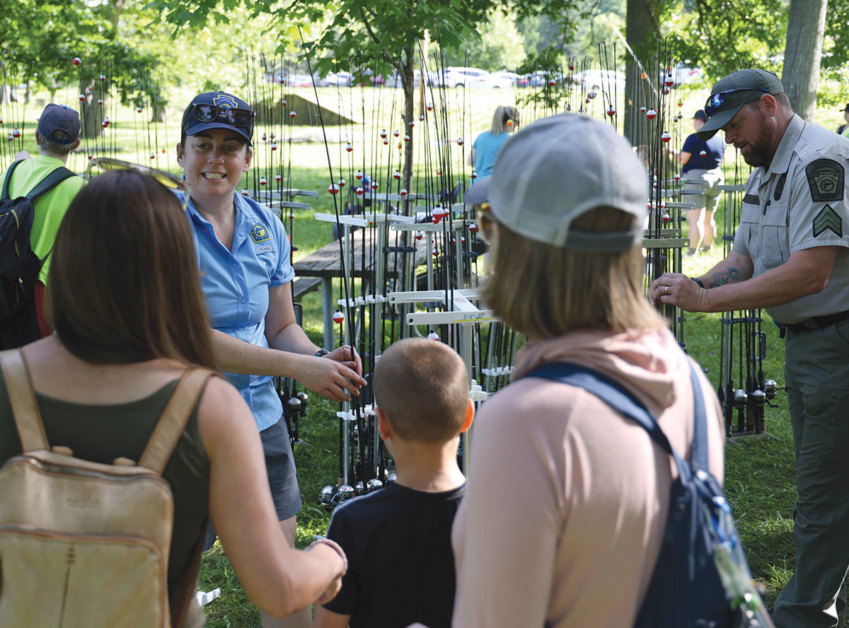 PFBC educator talking to a group of people while rigging up fishing rods.