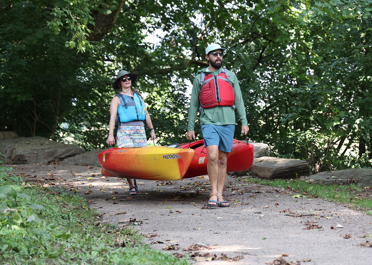 A woman and a man carrying two kayaks along a "carry-in" boat launch on the Conestoga River. 