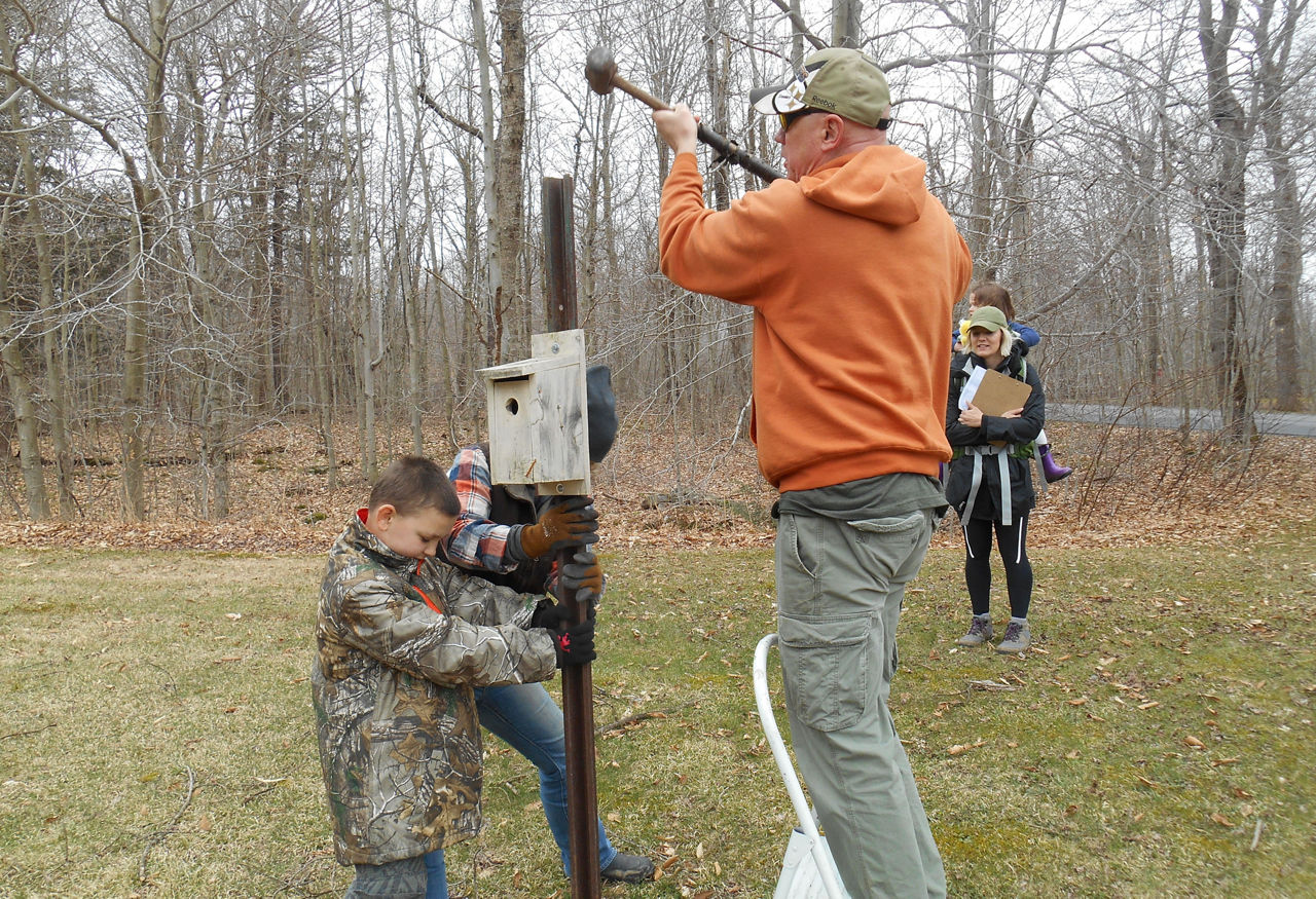 A family adjusting a nesting box. 