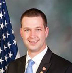 Matt Gabler smiles in portrait in front of American flag