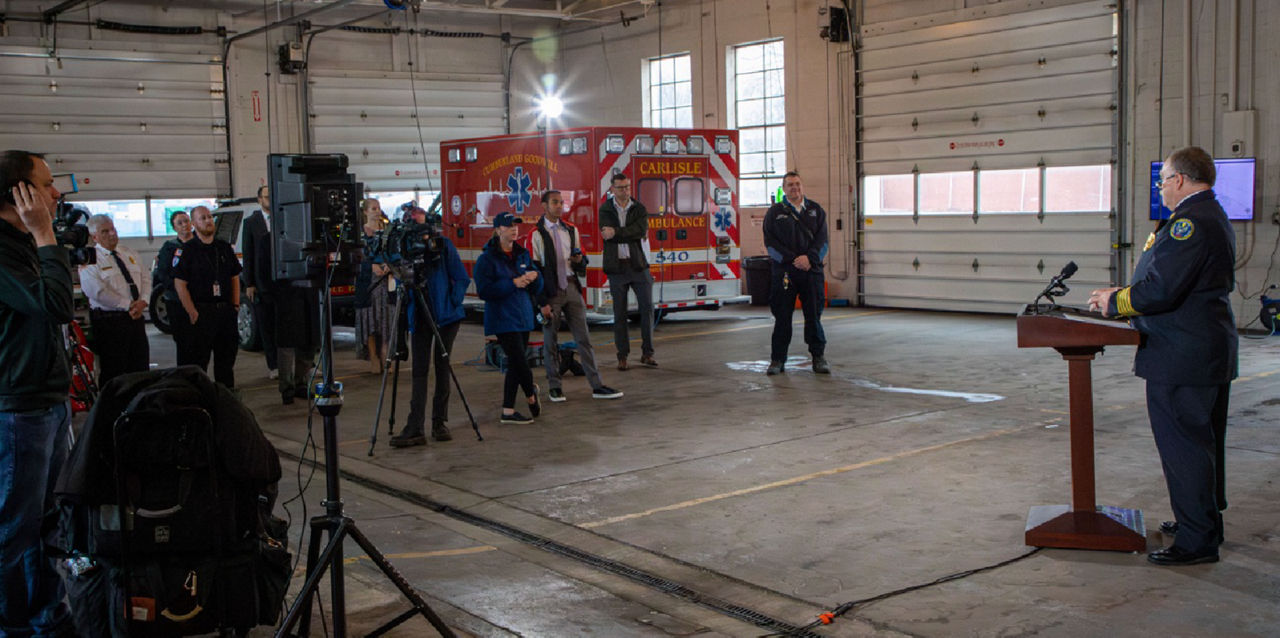 Fire Commissioner Tom Cook addresses a group of media members from inside an emergency medical facility.