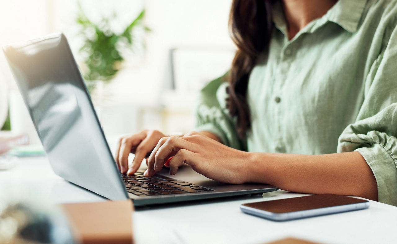 Creative professional at desk with computer and laptop, contacting the arts agency