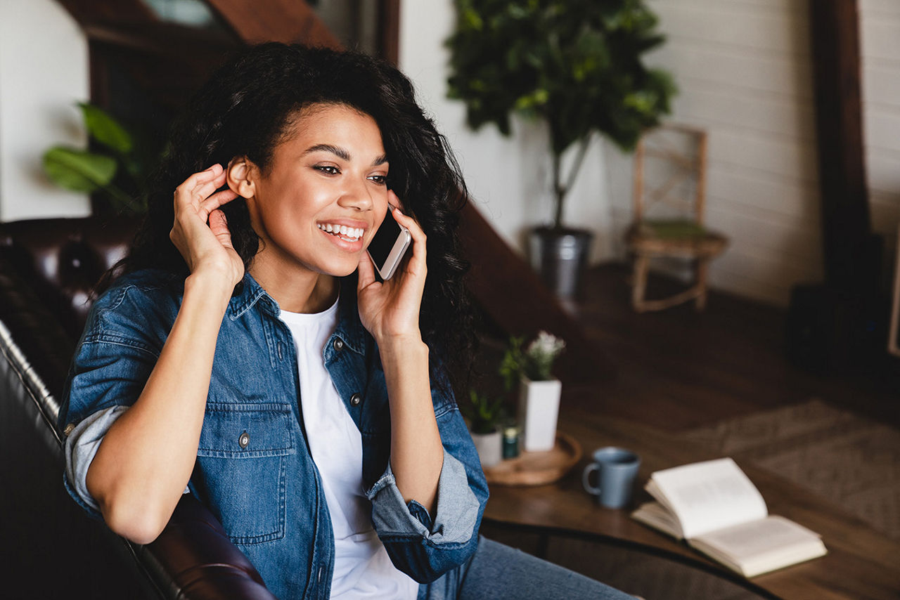 A woman talking on the phone while sitting on a couch at home