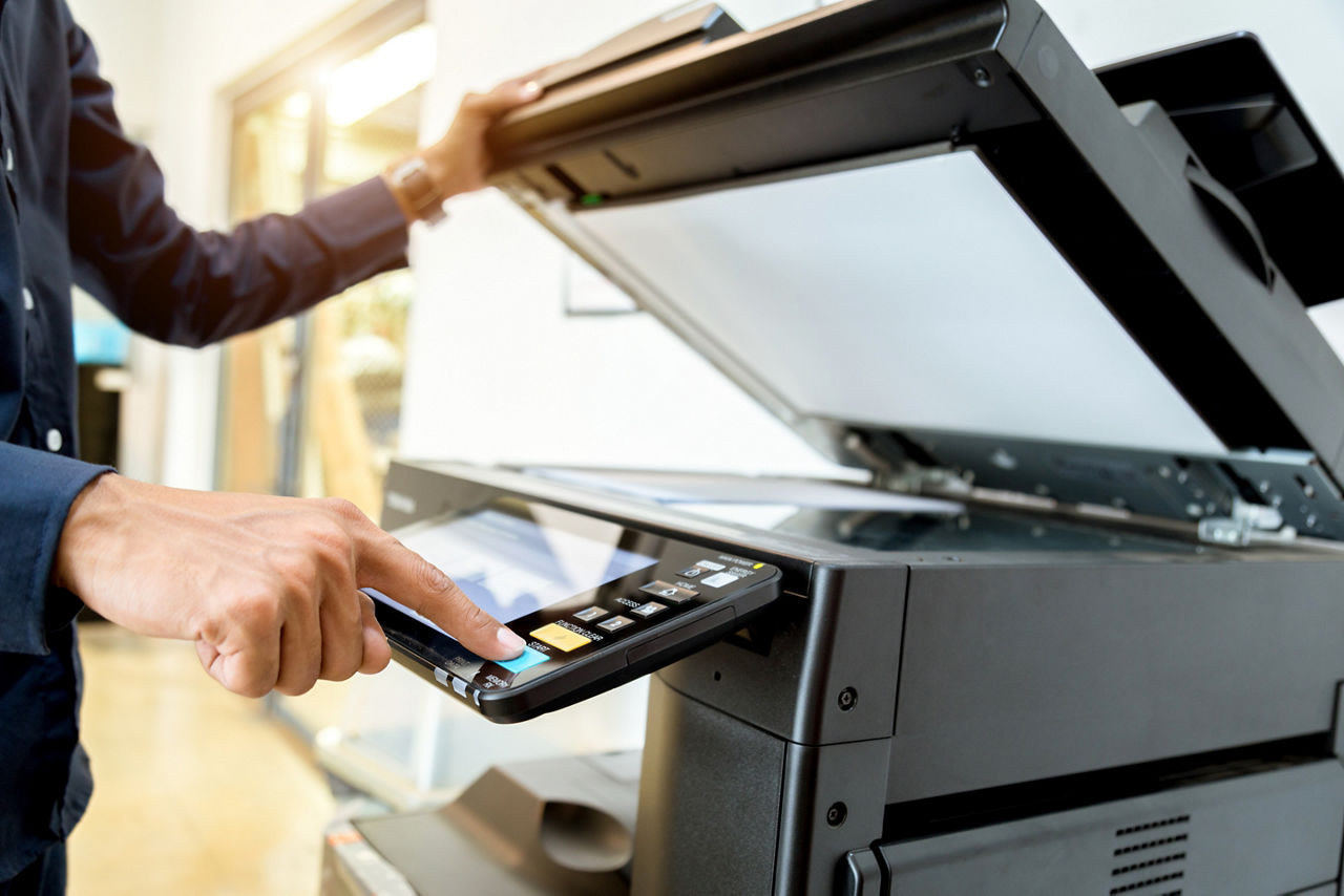 Employee pressing a button on a copier in the office.
