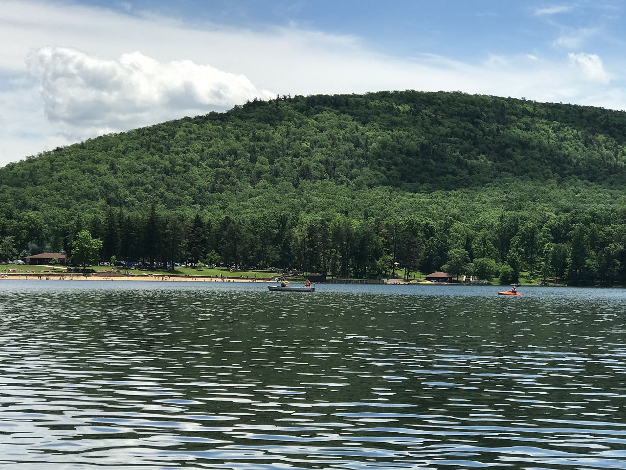 Kayakers paddling on the water with a deep green hill in the background