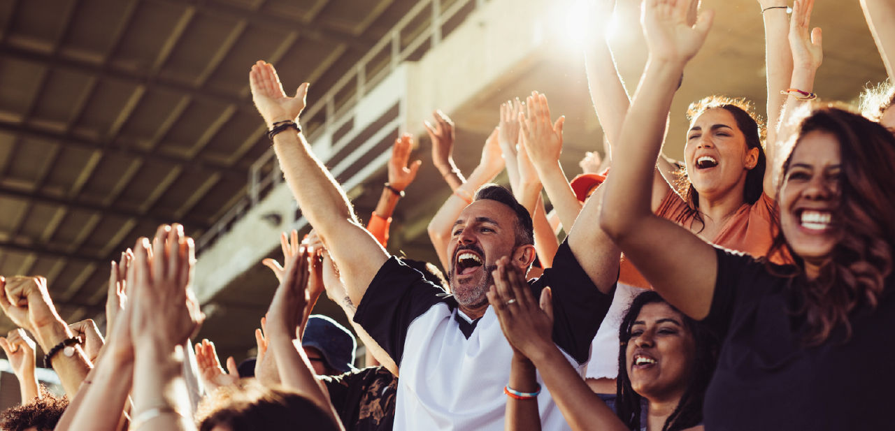 A crowd reacts happily in the stands of an event.