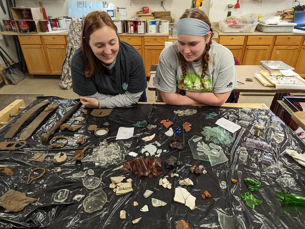Outdoor Corps Cultural Resources Crew members review artifacts on a desk.
