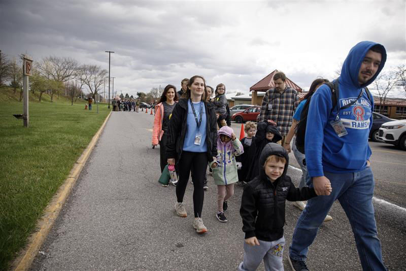 Several individuals stroll along a sidewalk during the Autism Awareness and Acceptance Walk, while a child walks closely behind
