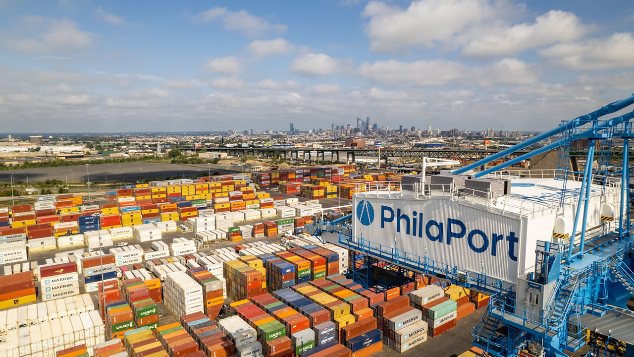 Photo of the port of Philadelphia from above. The image shows hundreds of shipping containers as well as a series of container lifts that read "PhilaPort" on the side.