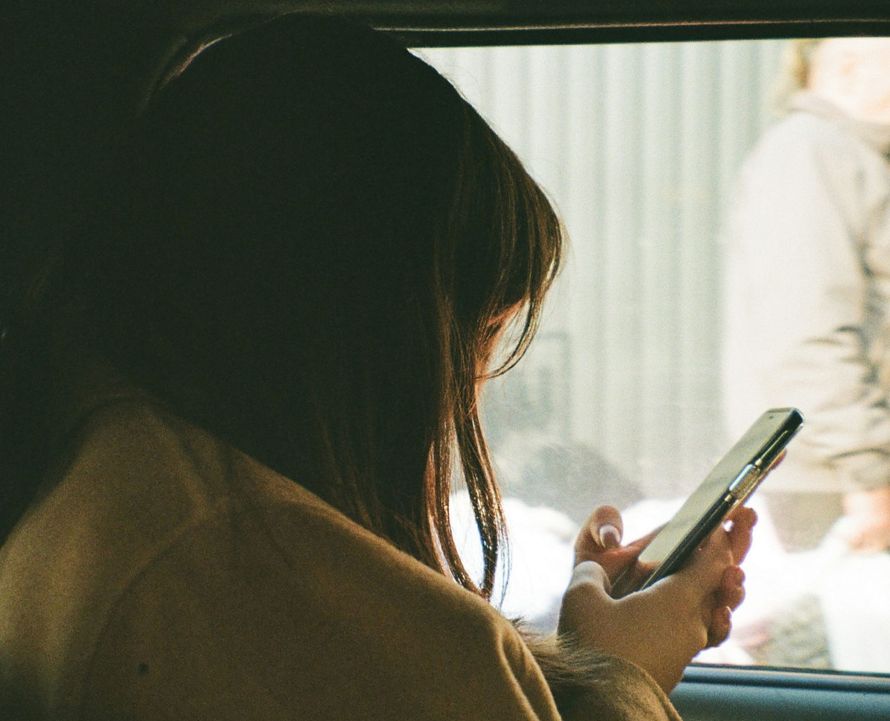 Girl sitting in car looking at cell phone