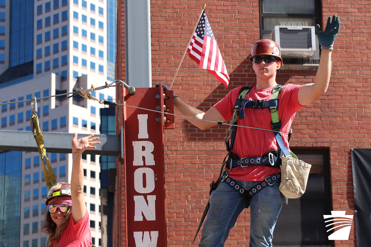 An ironworker apprentice waves from the Ironworker parade float in Pittsburgh, PA.